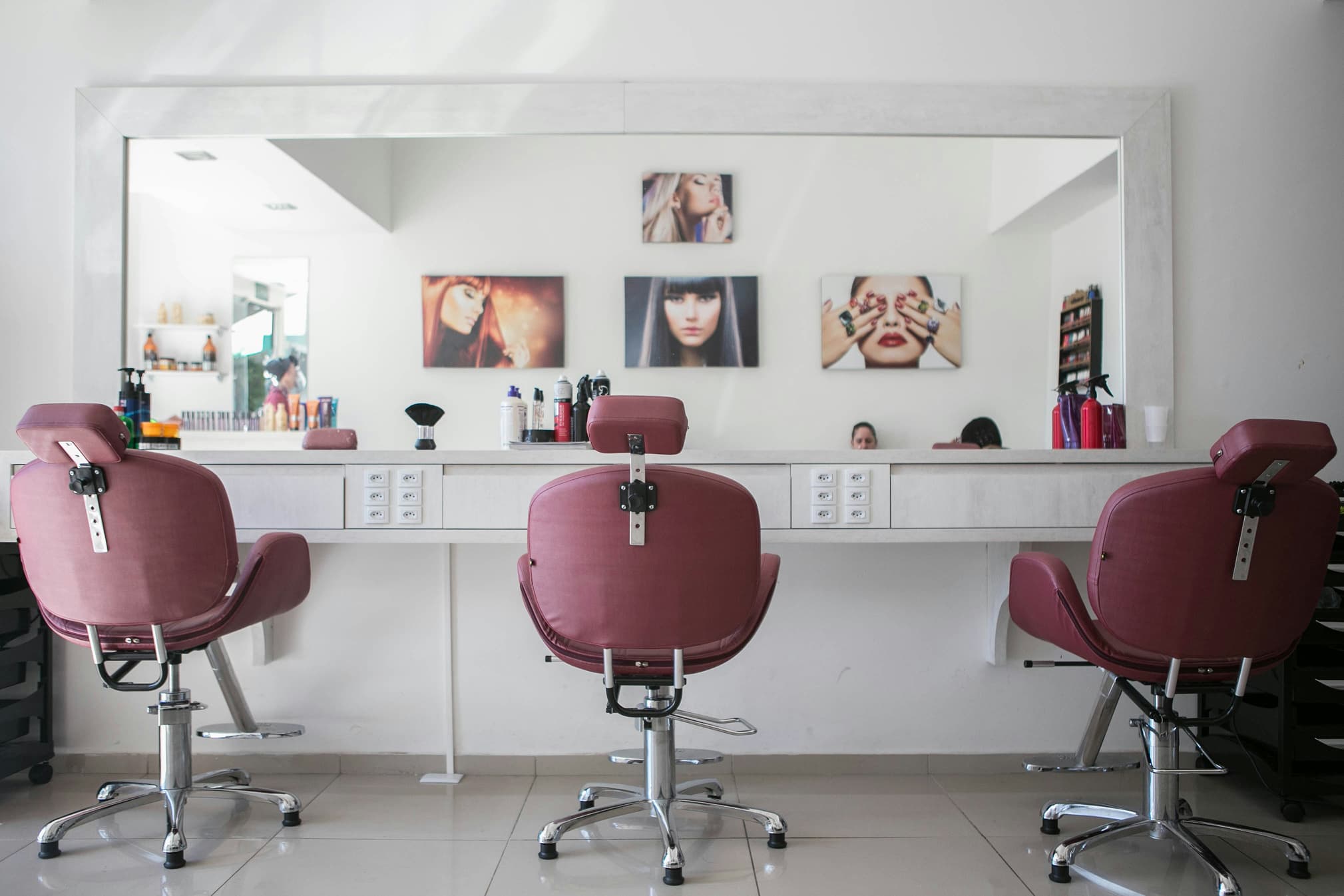 Three pink styling chairs facing a long salon mirror
